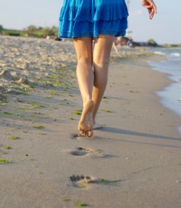 Barefoot woman walking on wet sand
